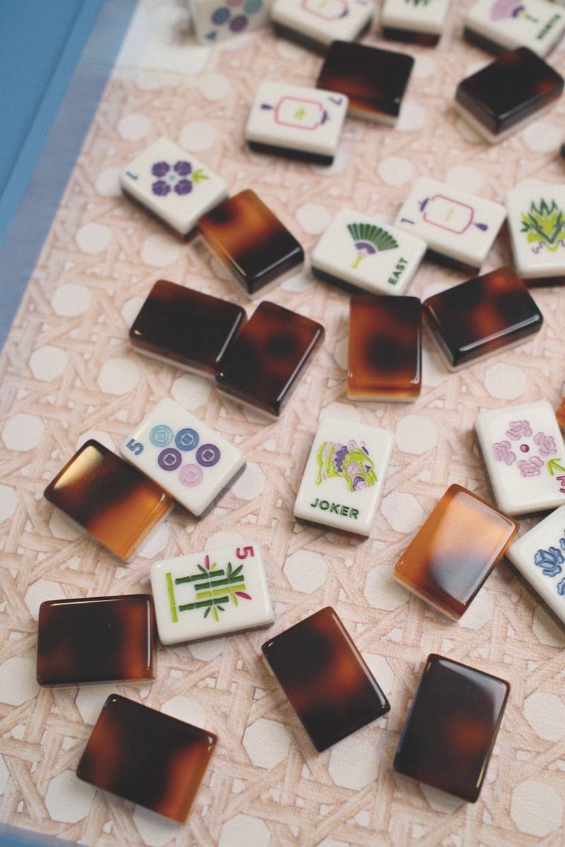 Tortoiseshell and hand-painted mahjong tiles on a cane mat